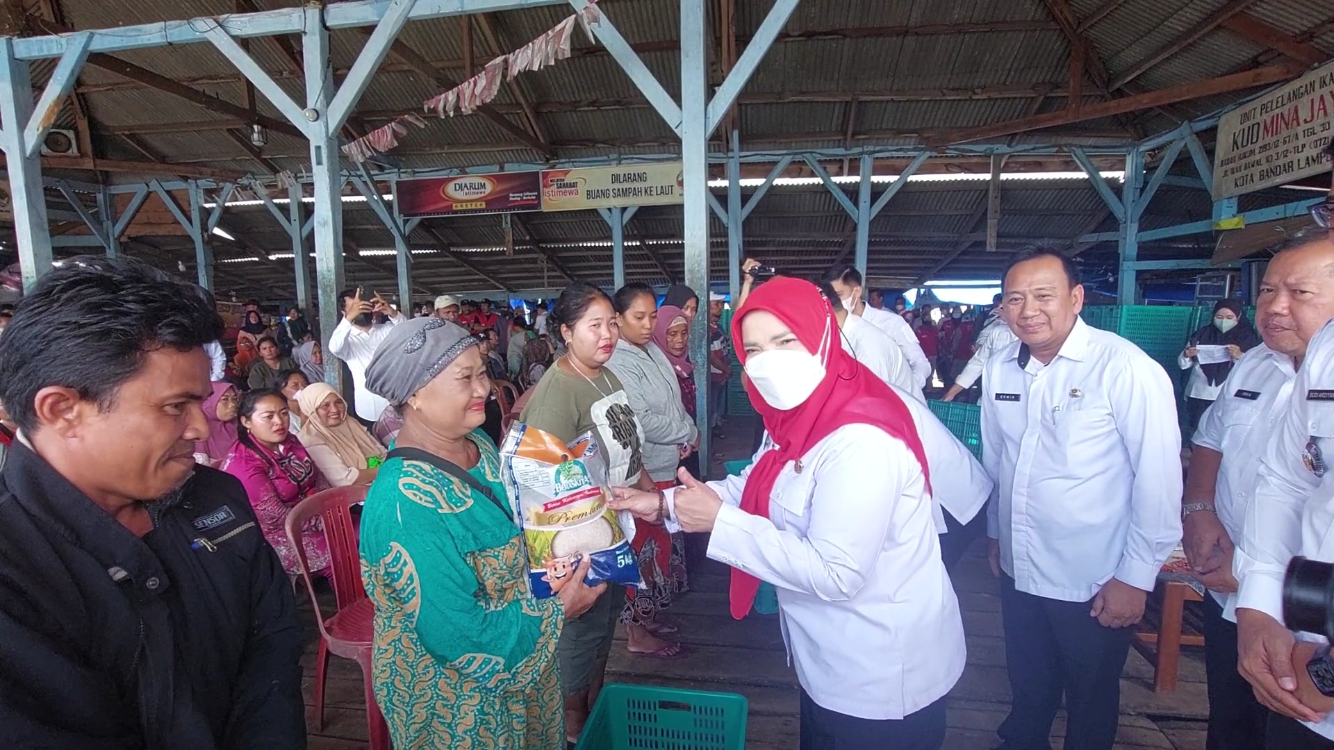 Walikota Bandar Lampung Eva Dwiana menyerahkan bantuan sarana dan prasarana serta beras kepada pedagang dan warga sekitar TPI Gudang Lelang || Foto Saibetik.com